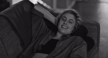 Movie still from “Frances Ha” (2012), directed by Noah Baumbach – A woman laying on a bed with her arms behind her head; Medium shot, High angle