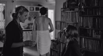 Movie still from “Frances Ha” (2012), directed by Noah Baumbach – Three women are talking in a room with a bookshelf in the background; Medium shot, Over the shoulder angle