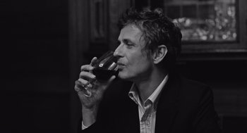 Movie still from “Frances Ha” (2012), directed by Noah Baumbach – A black and white photo of a man drinking a glass of red wine; Close Up shot, Low angle