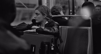Movie still from “Frances Ha” (2012), directed by Noah Baumbach – A woman sitting on a bus with her hand on her chin; Medium shot, Over the shoulder angle