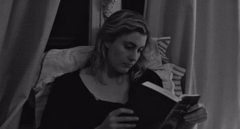 Movie still from “Frances Ha” (2012), directed by Noah Baumbach – A woman reading a book while sitting on a bed; Close Up shot, High angle