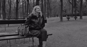 Movie still from “Frances Ha” (2012), directed by Noah Baumbach – A woman sitting on top of a bench in a park; Medium shot, Over the shoulder angle