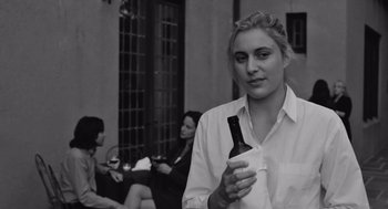 Movie still from “Frances Ha” (2012), directed by Noah Baumbach – A woman holding a bottle of wine in her hand; Close Up shot, Over the shoulder angle