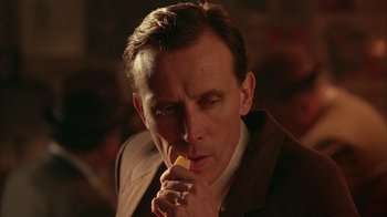 Movie still from “Naked Lunch” (1991), directed by David Cronenberg – A person holding a piece of food; Close Up shot, Low angle