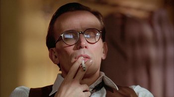 Movie still from “Naked Lunch” (1991), directed by David Cronenberg – A man with glasses is smoking a cigarette; Close Up shot, Low angle