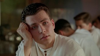 Movie still from “Naked Lunch” (1991), directed by David Cronenberg – A young man with his head resting on his hand; Close Up shot, Low angle