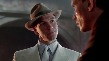 Movie still from “Naked Lunch” (1991), directed by David Cronenberg – A man wearing a suit and a hat talking to another man wearing a suit; Close Up shot, Low angle