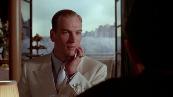Movie still from “Naked Lunch” (1991), directed by David Cronenberg – A man wearing a white suit and tie; Close Up shot, Over the shoulder angle