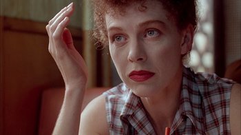 Movie still from “Naked Lunch” (1991), directed by David Cronenberg – A person sitting on a couch; Close Up shot, Low angle