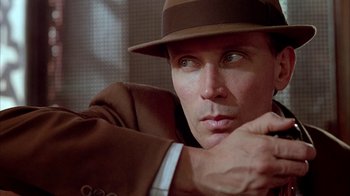 Movie still from “Naked Lunch” (1991), directed by David Cronenberg – A person wearing a suit and a hat; Close Up shot, Low angle