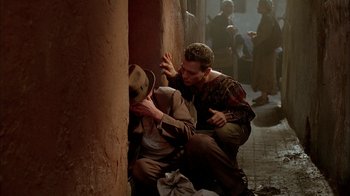 Movie still from “Naked Lunch” (1991), directed by David Cronenberg – Two men in the street , one of them leaning against a wall; Medium shot, Over the shoulder angle
