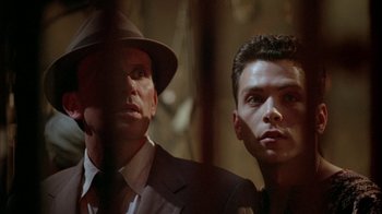 Movie still from “Naked Lunch” (1991), directed by David Cronenberg – A man in a suit and a hat standing next to another man in a suit and a hat; Close Up shot, Low angle
