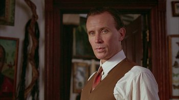 Movie still from “Naked Lunch” (1991), directed by David Cronenberg – A person wearing a suit and tie; Close Up shot, Low angle