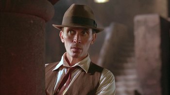 Movie still from “Naked Lunch” (1991), directed by David Cronenberg – A man wearing a hat and a tie; Close Up shot, Low angle