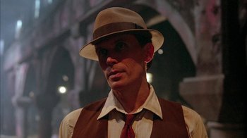 Movie still from “Naked Lunch” (1991), directed by David Cronenberg – A man wearing a hat and a tie; Close Up shot, Low angle
