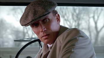 Movie still from “Naked Lunch” (1991), directed by David Cronenberg – A man wearing a hat sitting in the driver's seat of a car; Close Up shot, Low angle