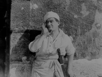 Movie still from “Napoleon” (1927), directed by Abel Gance – An old black and white photo of a man holding a knife; Medium shot, High angle