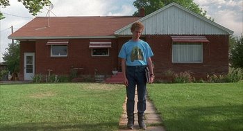 Movie still from “Napoleon Dynamite” (2004), directed by Jared Hess – A man standing on a brick walkway in front of a house; Wide shot, Low angle