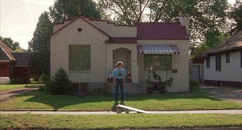 Movie still from “Napoleon Dynamite” (2004), directed by Jared Hess – A person standing in front of a house; Wide shot, Low angle