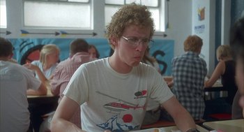 Movie still from “Napoleon Dynamite” (2004), directed by Jared Hess – A young man sitting in front of a plate of food at a table; Medium shot, Over the shoulder angle