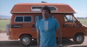 Movie still from “Napoleon Dynamite” (2004), directed by Jared Hess – A man standing in front of an orange van; Medium shot, Low angle