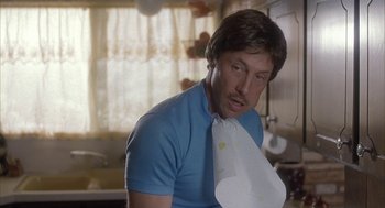 Movie still from “Napoleon Dynamite” (2004), directed by Jared Hess – A man in a blue t - shirt holding a paper towel; Close Up shot, Low angle