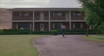 Movie still from “Napoleon Dynamite” (2004), directed by Jared Hess – A man walking in front of a large building; Extreme Wide shot, Low angle
