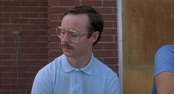 Movie still from “Napoleon Dynamite” (2004), directed by Jared Hess – A man wearing glasses and a blue polo shirt; Close Up shot, Low angle