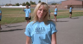 Movie still from “Napoleon Dynamite” (2004), directed by Jared Hess – A woman in a blue shirt is standing in a parking lot; Close Up shot, Low angle