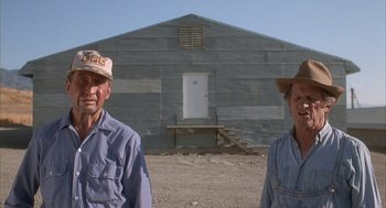 Movie still from “Napoleon Dynamite” (2004), directed by Jared Hess – Two men standing in front of a building; Wide shot, Low angle