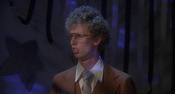 Movie still from “Napoleon Dynamite” (2004), directed by Jared Hess – A man in a suit and tie with a wig; Close Up shot, Low angle