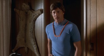 Movie still from “Napoleon Dynamite” (2004), directed by Jared Hess – A man standing in front of a wooden door; Medium shot, Low angle