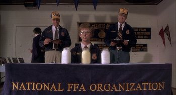 Movie still from “Napoleon Dynamite” (2004), directed by Jared Hess – A group of men standing around a table; Medium shot, Overhead angle