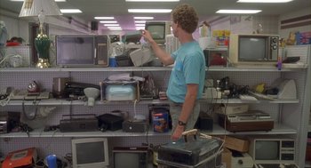 Movie still from “Napoleon Dynamite” (2004), directed by Jared Hess – A man standing in front of a shelf of electronics; Medium shot, Low angle