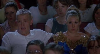 Movie still from “Napoleon Dynamite” (2004), directed by Jared Hess – A group of people sitting in a room; Medium shot, Over the shoulder angle