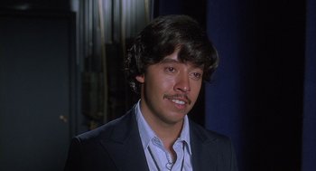 Movie still from “Napoleon Dynamite” (2004), directed by Jared Hess – A man in a black suit and white shirt; Close Up shot, Over the shoulder angle