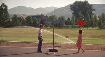 Movie still from “Napoleon Dynamite” (2004), directed by Jared Hess – A boy and a little girl are playing with a sprinkler; Extreme Wide shot, High angle
