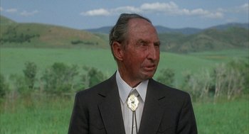Movie still from “Napoleon Dynamite” (2004), directed by Jared Hess – An older man wearing a suit and tie; Close Up shot, Over the shoulder angle