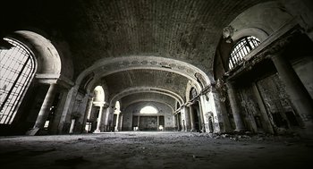 Movie still from “Naqoyqatsi” (2002), directed by Godfrey Reggio – An old building with a large arch ceiling; Extreme Wide shot, Low angle