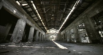 Movie still from “Naqoyqatsi” (2002), directed by Godfrey Reggio – An abandoned building with a lot of windows; Extreme Wide shot, Low angle