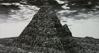 Movie still from “Naqoyqatsi” (2002), directed by Godfrey Reggio – A black and white painting of a pyramid in the middle of the night; Extreme Wide shot, Low angle