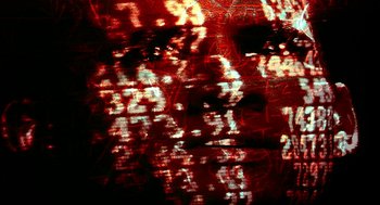 Movie still from “Naqoyqatsi” (2002), directed by Godfrey Reggio – A blurry image of a face with a red background; Extreme Close Up shot, Low angle