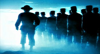 Movie still from “Naqoyqatsi” (2002), directed by Godfrey Reggio – A group of men standing next to each other in the fog; Wide shot, Low angle