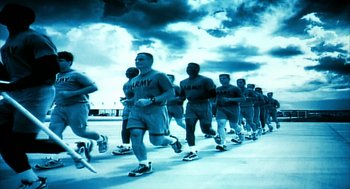 Movie still from “Naqoyqatsi” (2002), directed by Godfrey Reggio – A large group of men are running together; Wide shot, Low angle