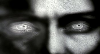 Movie still from “Naqoyqatsi” (2002), directed by Godfrey Reggio – A black and white photo of a man's eyes; Extreme Close Up shot, Overhead angle