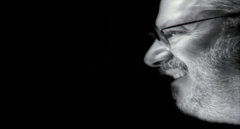 Movie still from “Naqoyqatsi” (2002), directed by Godfrey Reggio – A black and white photo of a man with a beard; Extreme Close Up shot, Low angle