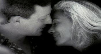 Movie still from “Naqoyqatsi” (2002), directed by Godfrey Reggio – A man and a woman face to face with their noses touching; Close Up shot, Overhead angle