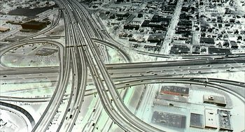 Movie still from “Naqoyqatsi” (2002), directed by Godfrey Reggio – An aerial view of an intersection in a city; Extreme Wide shot, High angle