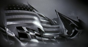 Movie still from “Naqoyqatsi” (2002), directed by Godfrey Reggio – A black and white photo of a bunch of american flags; Extreme Close Up shot, Low angle