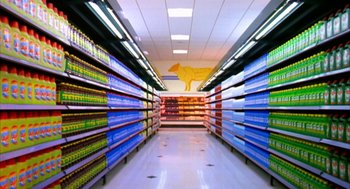 Movie still from “Naqoyqatsi” (2002), directed by Godfrey Reggio – A grocery store aisle filled with lots of shelves of food; Extreme Wide shot, High angle
